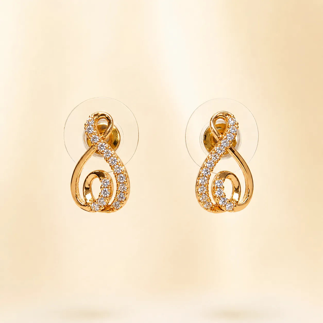 "Gold swirl stud earrings with pave crystals at an angle"