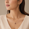 Model wearing gold ruby halo pendant necklace and matching stud earring