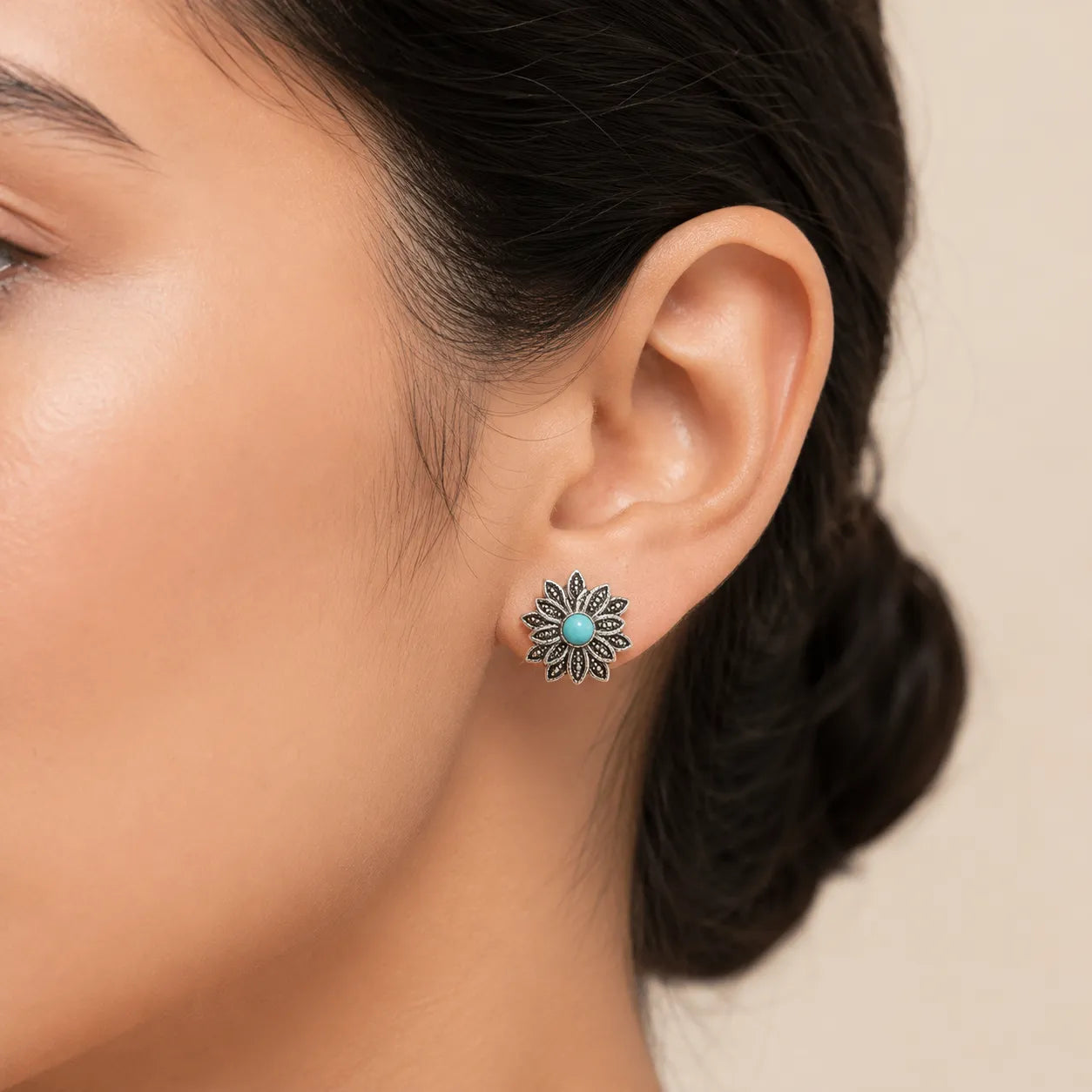 "Woman wearing silver flower stud earring with turquoise center stone"