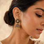 Woman wearing antique gold ruby emerald floral jhumka earrings with pearl drops and champagne crystal dome styled with cream silk saree