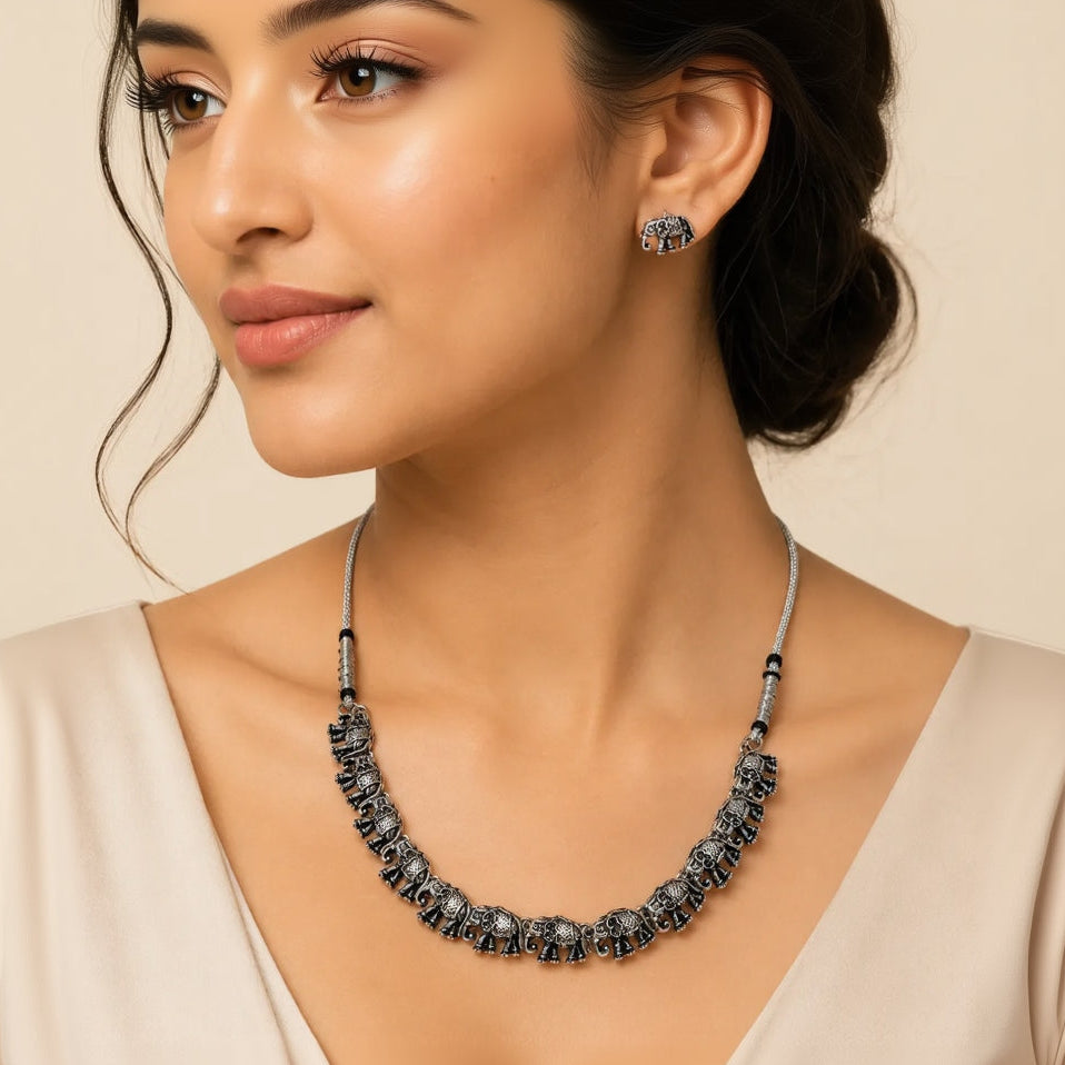"Woman wearing oxidized silver elephant choker necklace and matching stud earrings"