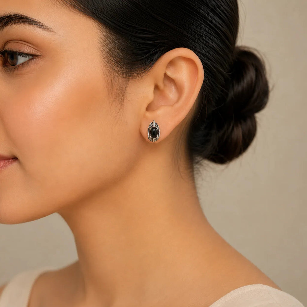 "Woman wearing black onyx leaf-shaped stud earring with silver detailing"