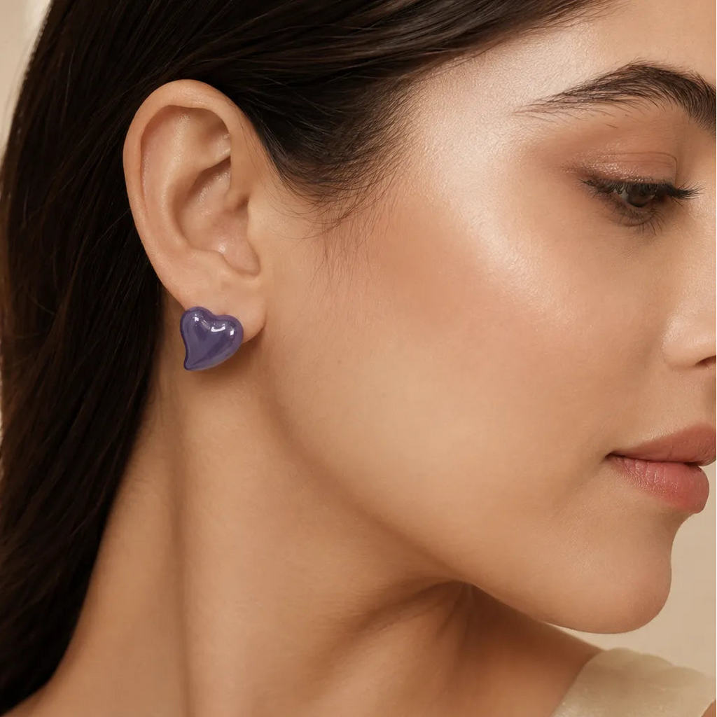 Woman wearing glossy lavender purple puffy heart stud earring styled with cream sleeveless top