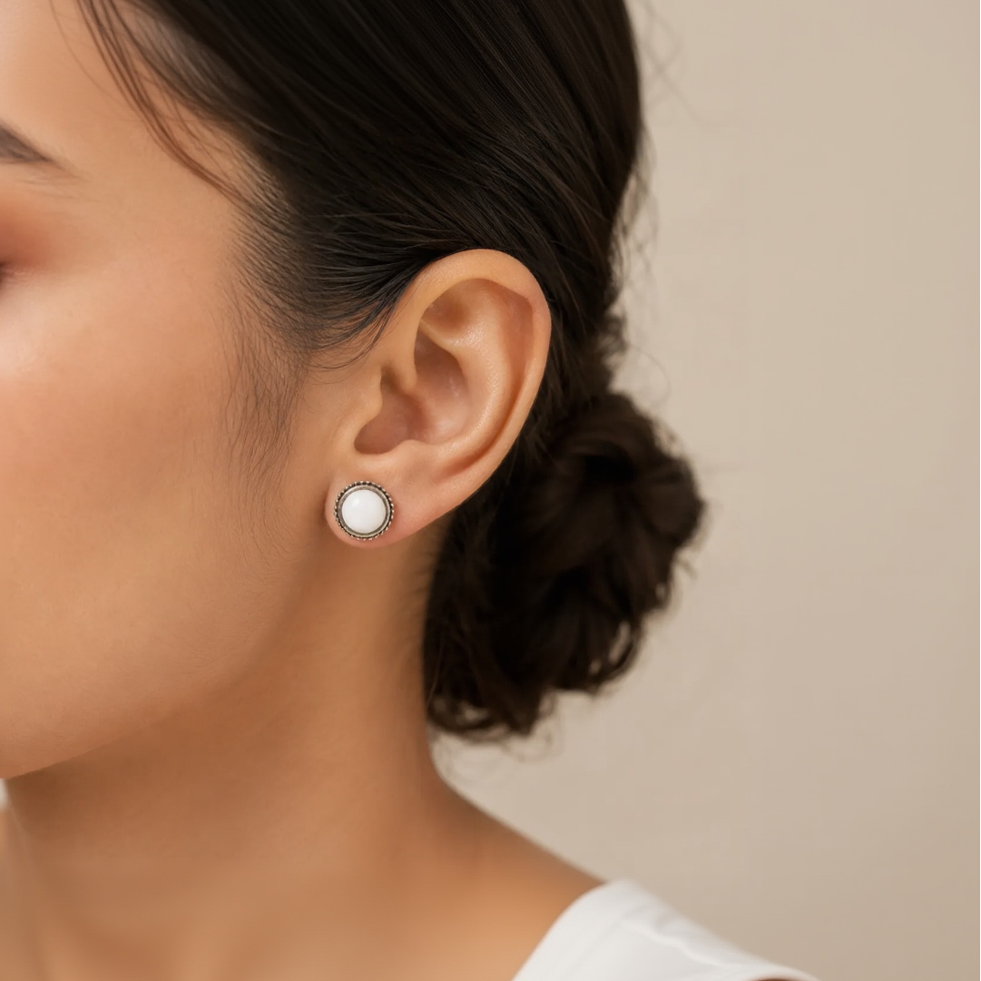  "Woman wearing white stone round stud earring with beaded silver border"