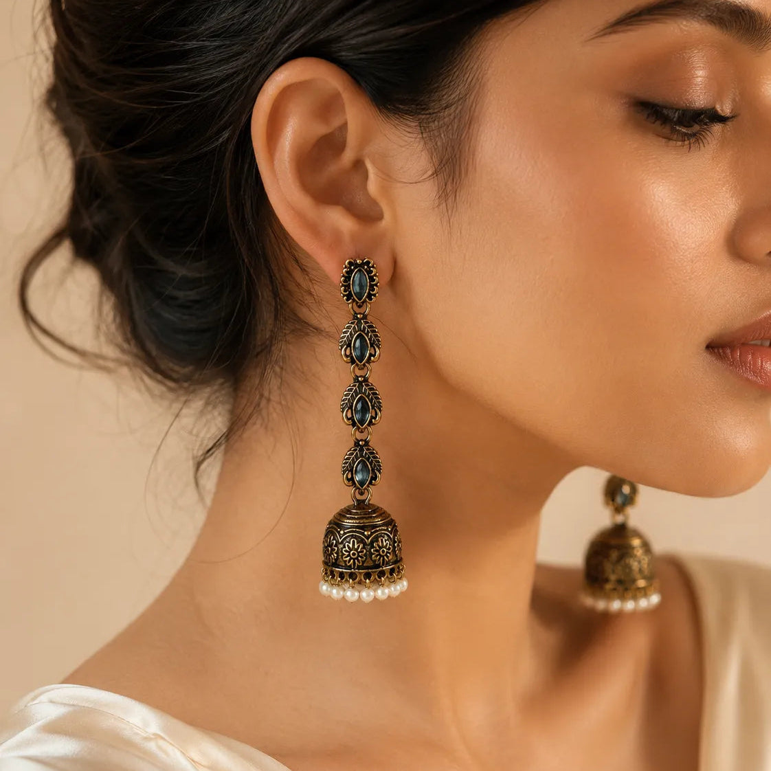 Woman wearing antique gold jhumka earring with blue crystal and pearl fringe, close-up ethnic jewelry photo