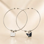 Silver smiley face and black butterfly enamel charm bangle bracelet set of 2 overlapping on beige background