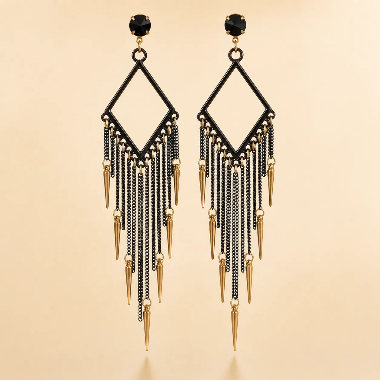 Black chandelier fringe earrings with gold spike charms, geometric diamond frame and black crystal stud, front view on beige background