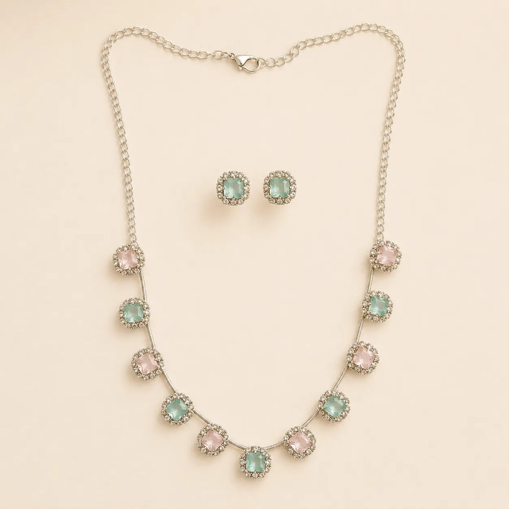 Pink and mint crystal halo necklace and earring set coiled on beige fabric, showing extendable chain and clasp detail