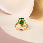 "Back view of pear-shaped emerald ring showing gold prong setting and band"