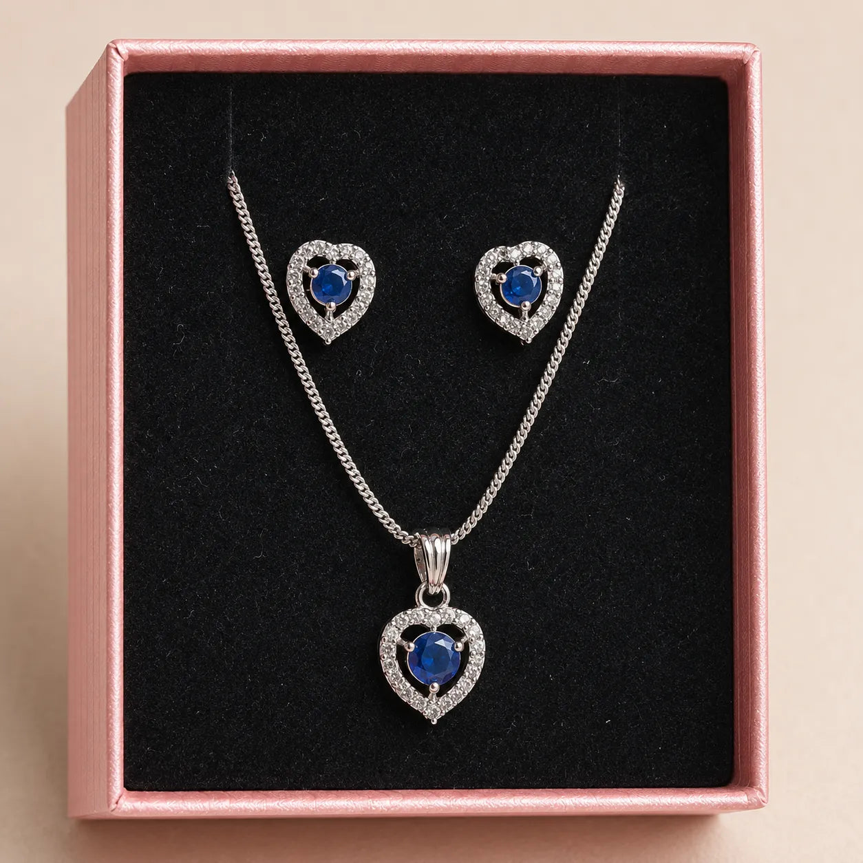 Blue heart pendant necklace and matching earrings displayed in pink gift box