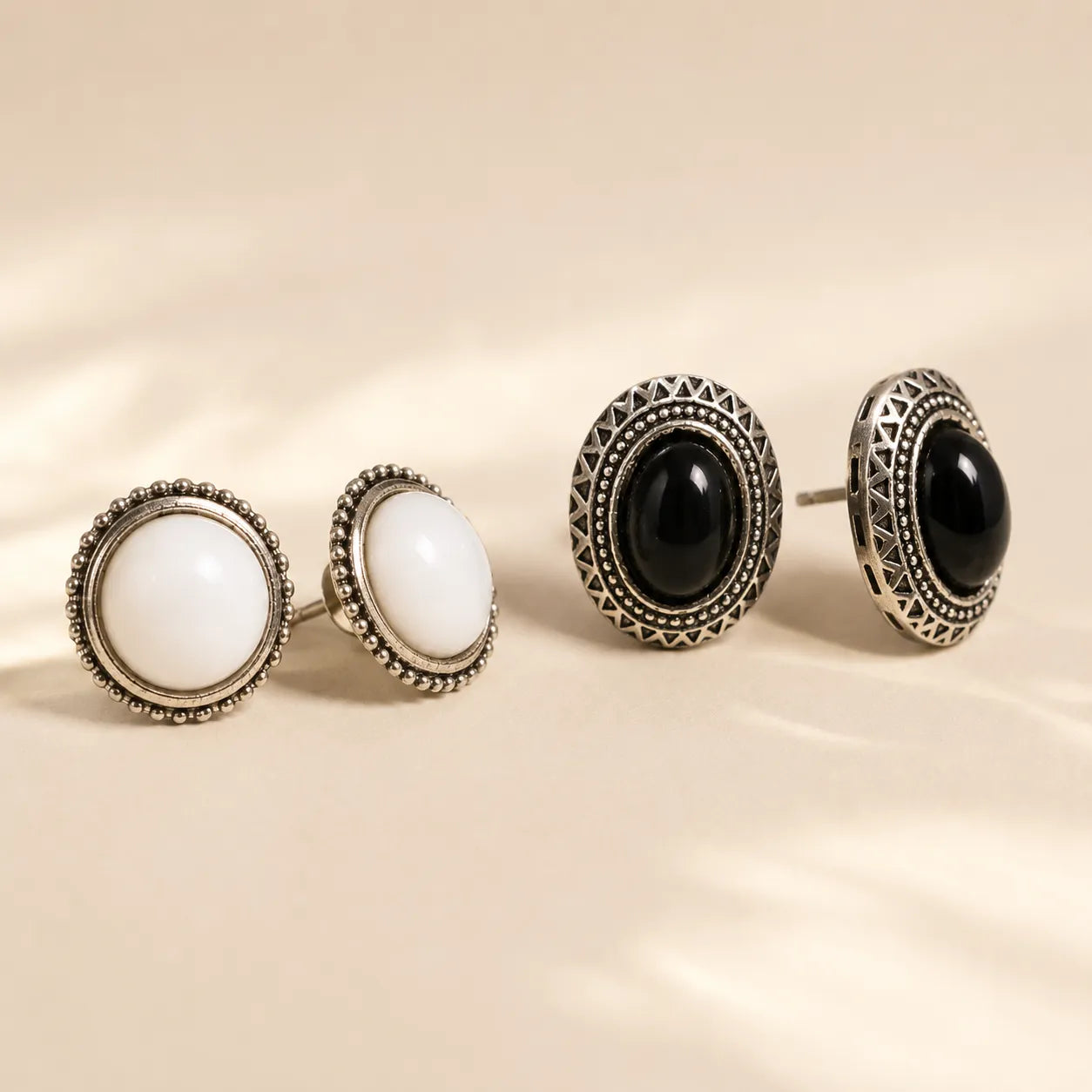"Black and white stone stud earrings side by side showing silver beaded detail"