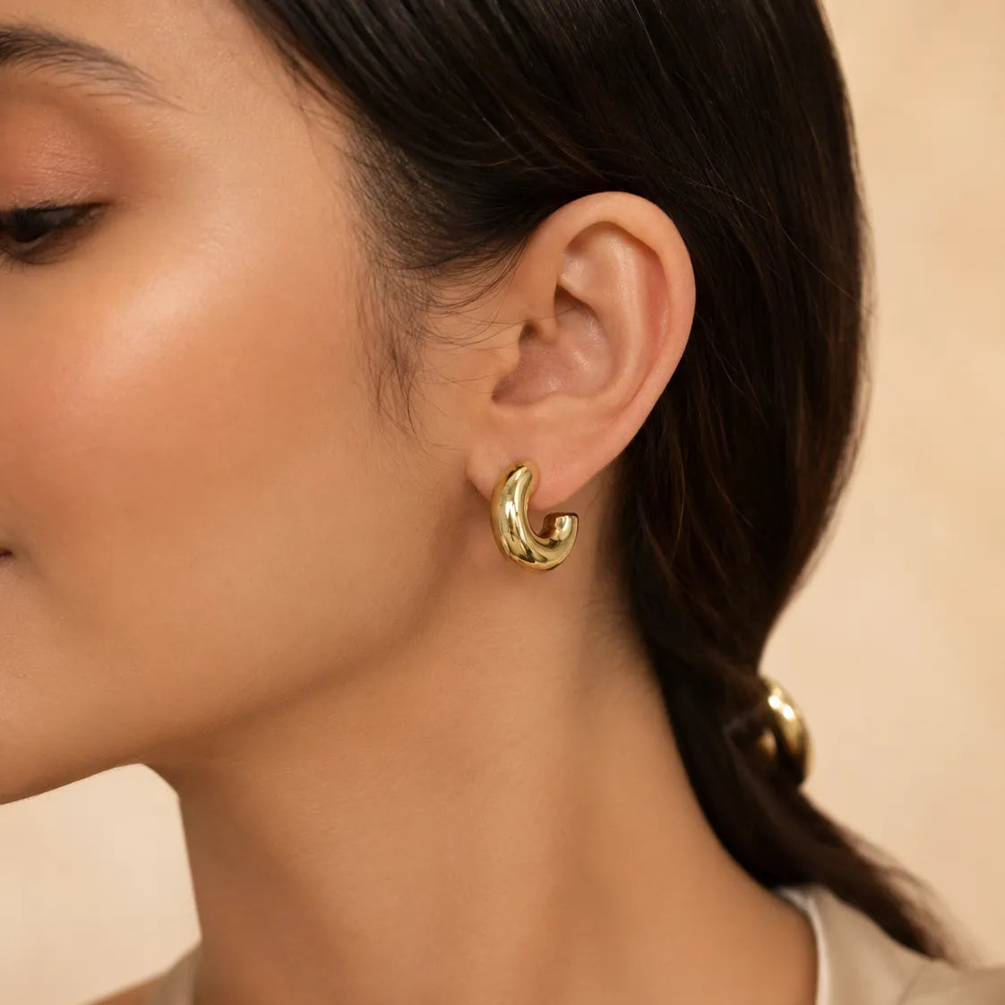  "Woman wearing chunky gold hoop earring with sleek hairstyle"