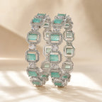Set of two silver mint green emerald cut CZ pave halo bangle bracelets displayed upright showing full stone detail and sparkle