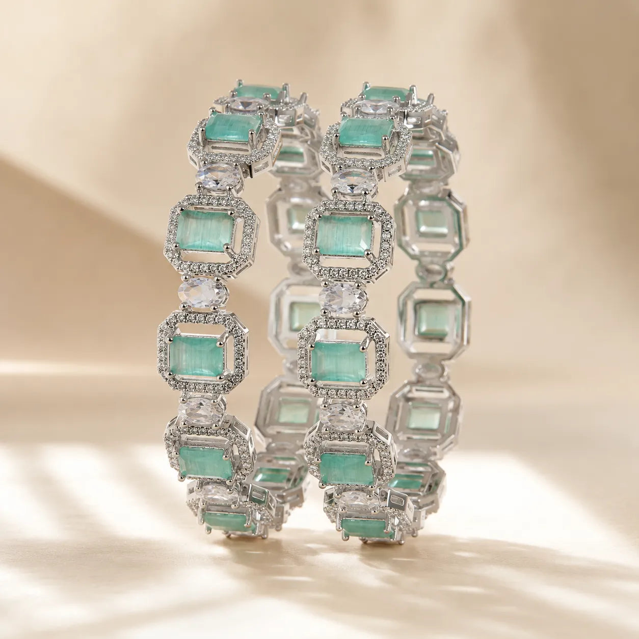 Set of two silver mint green emerald cut CZ pave halo bangle bracelets displayed upright showing full stone detail and sparkle