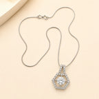 Silver hexagon halo necklace with round cut CZ center stone and double-bail chain detail on beige background