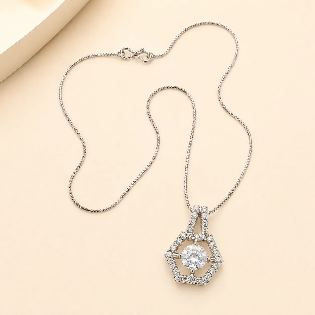 Silver hexagon halo necklace with round cut CZ center stone and double-bail chain detail on beige background
