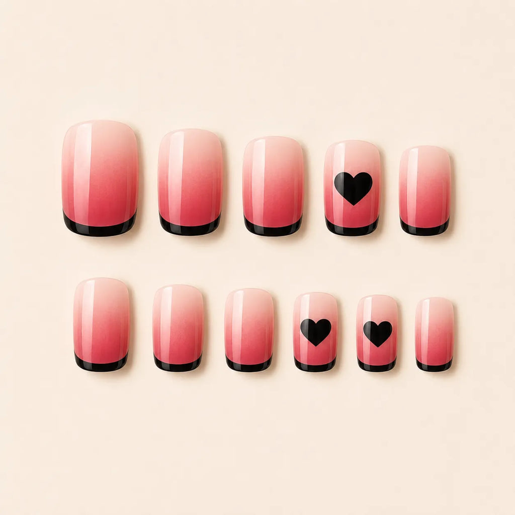 SAVNI pink ombre press-on nails with black French tips and heart accents, glossy fake nail set on beige background
