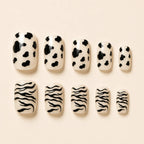SAVNI cow print and zebra print press-on nails, 10-piece glossy animal print fake nail set on beige background