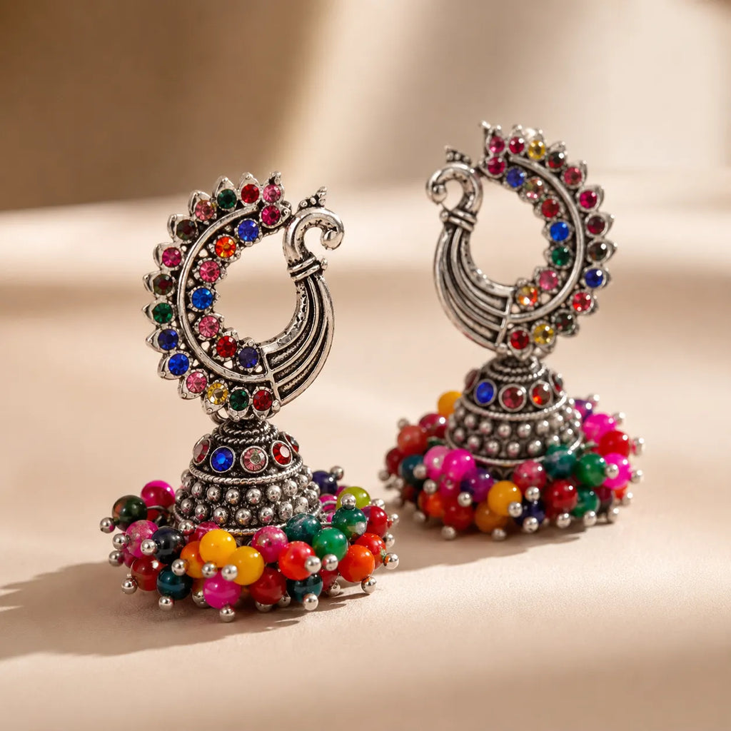 Colorful earrings with multicolored beads and gemstones on a beige background