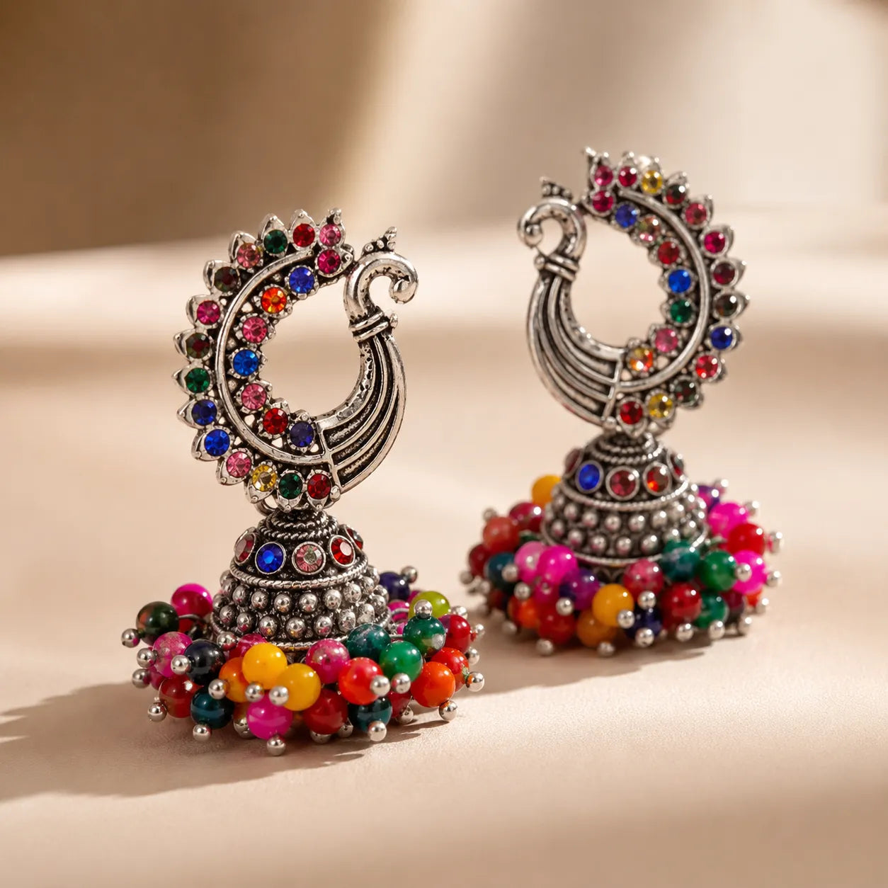 Colorful earrings with multicolored beads and gemstones on a beige background