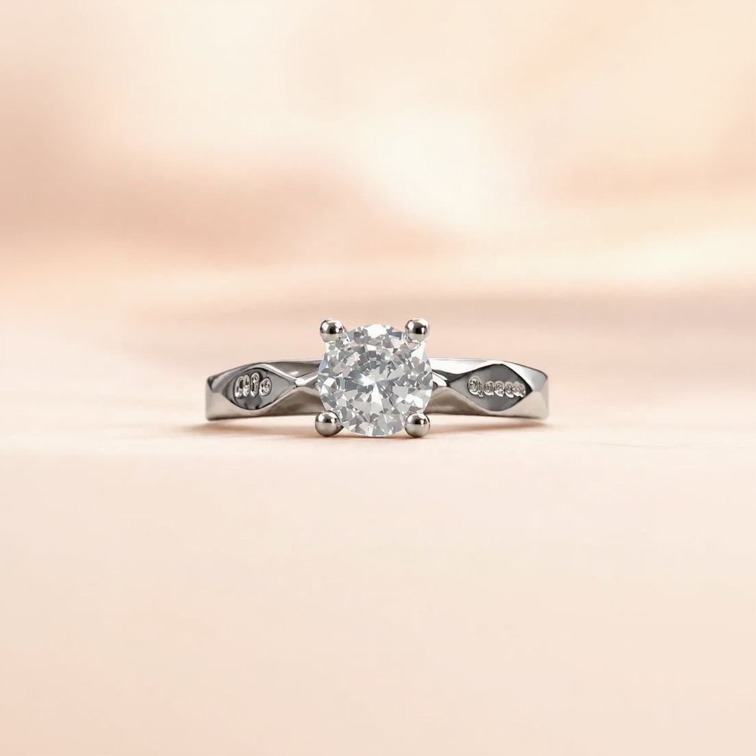 Silver solitaire ring with engraved script detail on both shoulders of the band, front facing close-up