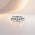 Round cut solitaire engagement ring in sterling silver with faceted shoulder detail, close-up front view on pink background