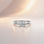 Round cut solitaire engagement ring in sterling silver with faceted shoulder detail, close-up front view on pink background