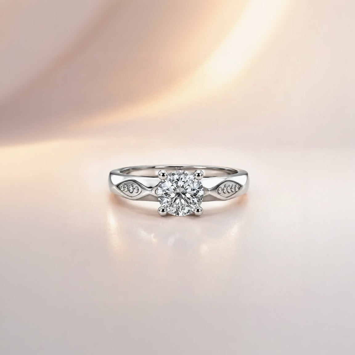 Round cut solitaire engagement ring in sterling silver with faceted shoulder detail, close-up front view on pink background